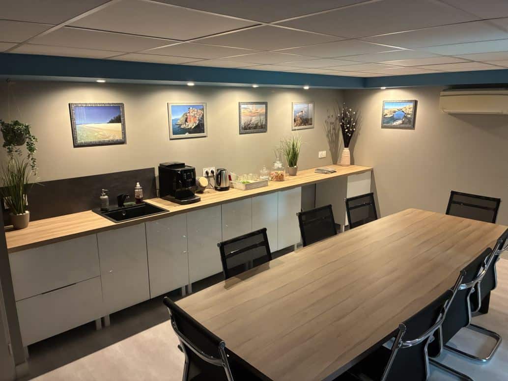 Salle de réunion avec grande table, espace café et cadres